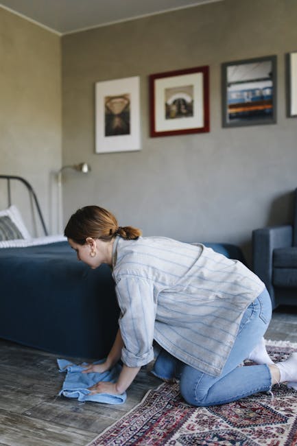 A person kneeling on a patterned carpet in a domestic setting, loading a white cleaning cloth into the yellow and black vacuum cleaner's dust compartment, with the vacuum’s flexible hose attached to